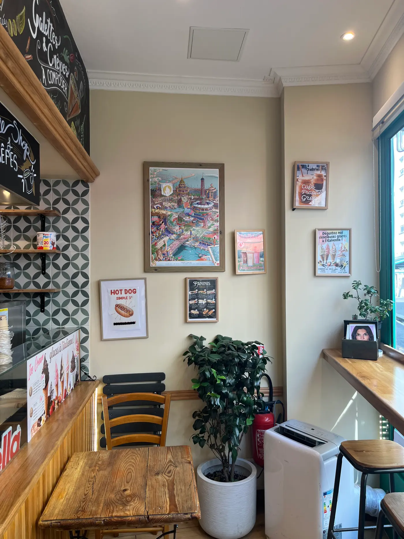 Coin salle de la crêperie : affiches, plantes et carrelage à motifs