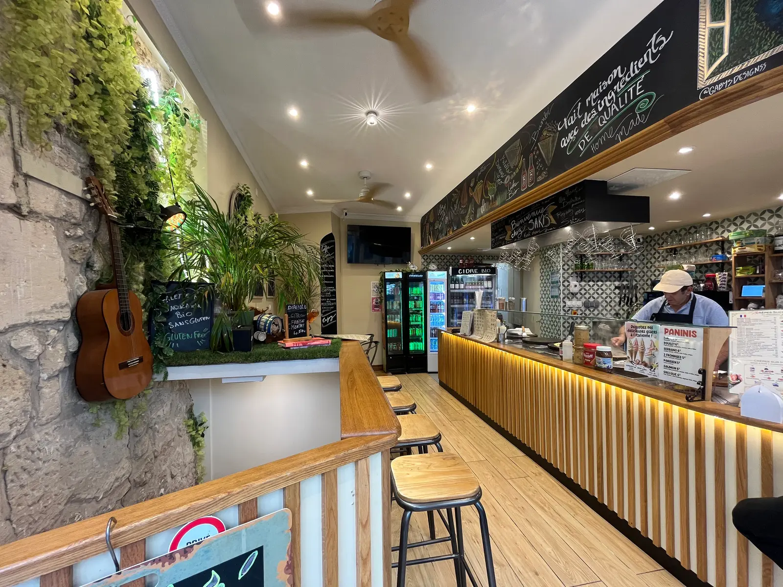 Salle de la Crêperie Sakis : comptoir en bois, mur végétal et ambiance conviviale